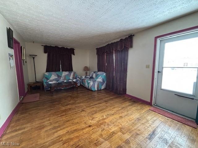 unfurnished living room with wood-type flooring, a textured ceiling, and a wealth of natural light