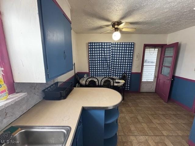 kitchen with blue cabinets, sink, and a textured ceiling