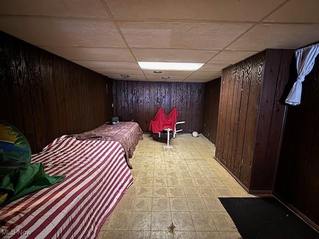 bedroom with a paneled ceiling and wood walls