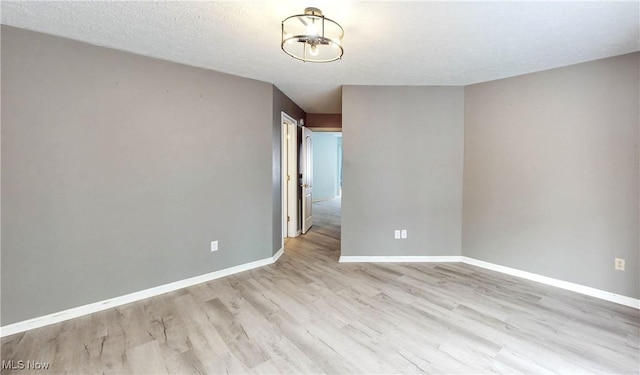 unfurnished room with a textured ceiling and light hardwood / wood-style floors