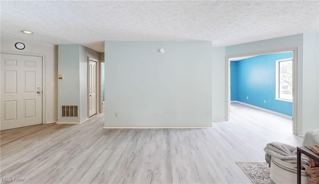 unfurnished room with light hardwood / wood-style floors and a textured ceiling