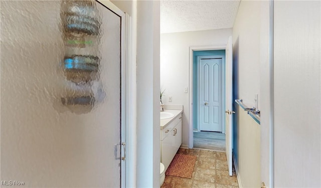 bathroom with vanity, an enclosed shower, a textured ceiling, and toilet