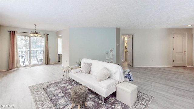 living room featuring a textured ceiling, a chandelier, and light hardwood / wood-style flooring