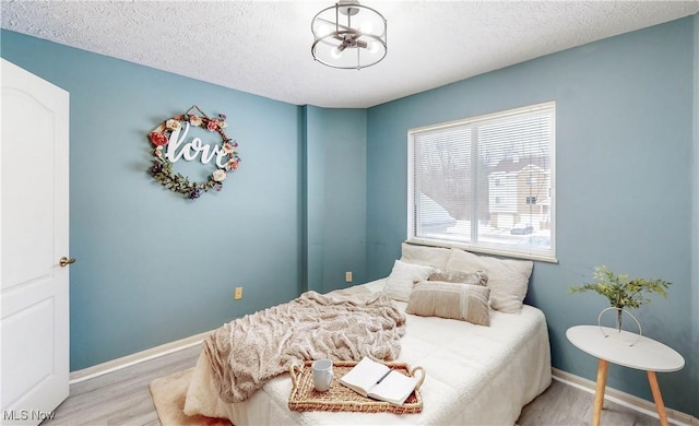 bedroom featuring light hardwood / wood-style flooring and a textured ceiling