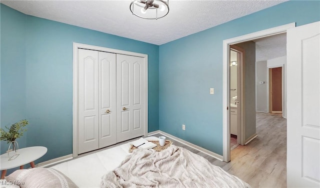 bedroom featuring light hardwood / wood-style floors, a closet, and a textured ceiling