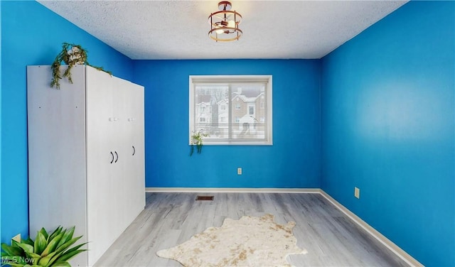 spare room featuring a textured ceiling and light wood-type flooring