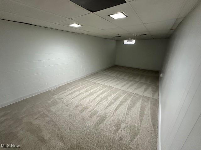 below grade area with light carpet and a paneled ceiling