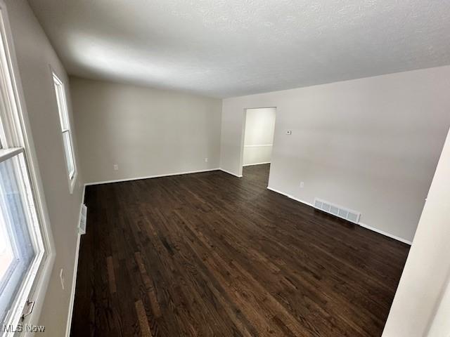 spare room with dark wood-style floors and baseboards