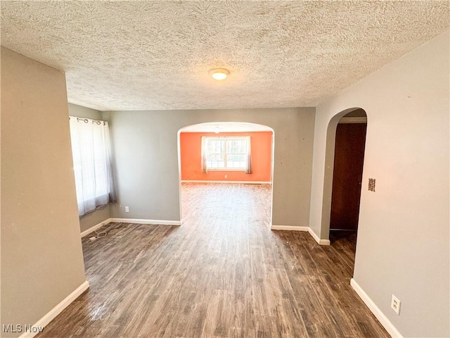 empty room featuring a wealth of natural light, dark hardwood / wood-style floors, and a textured ceiling