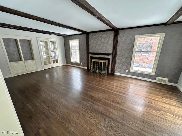 unfurnished living room with beamed ceiling, dark wood-type flooring, and french doors