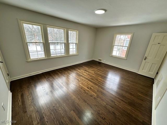 empty room featuring a wealth of natural light and dark hardwood / wood-style floors