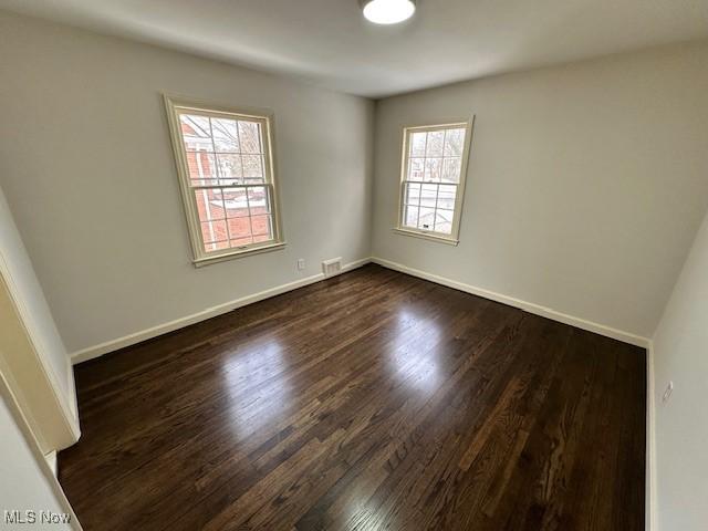 spare room with dark wood-type flooring and a wealth of natural light