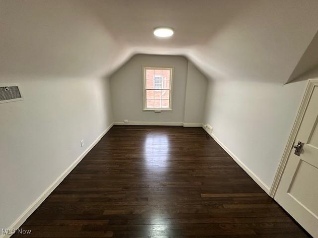 additional living space featuring dark wood-type flooring and vaulted ceiling