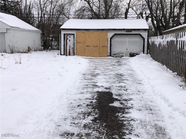 snowy yard featuring a garage and an outdoor structure