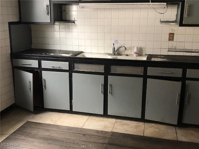 kitchen with black electric stovetop, sink, light tile patterned floors, and decorative backsplash