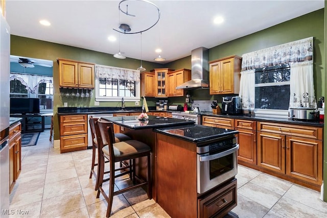 1011 Genesee Dr, Youngstown, OH 44511 - kitchen featuring wall chimney exhaust hood, a breakfast bar area, light tile patterned floors, stainless steel dishwasher, and a kitchen island