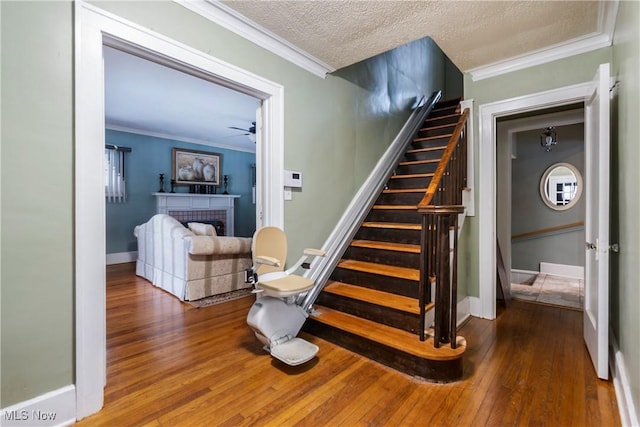 1011 Genesee Dr, Youngstown, OH 44511 - staircase featuring a tiled fireplace, hardwood / wood-style floors, crown molding, and a textured ceiling