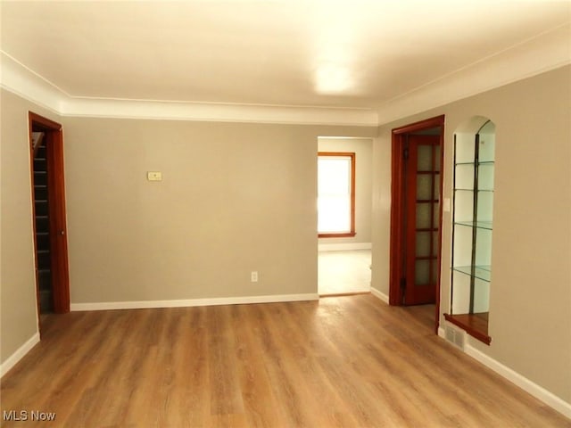 spare room with hardwood / wood-style flooring, ornamental molding, and built in features