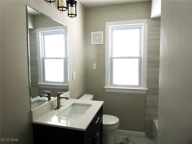 bathroom featuring a tub to relax in, vanity, and toilet