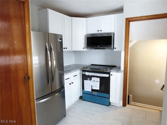 kitchen featuring dark stone countertops, white cabinets, stainless steel appliances, and backsplash