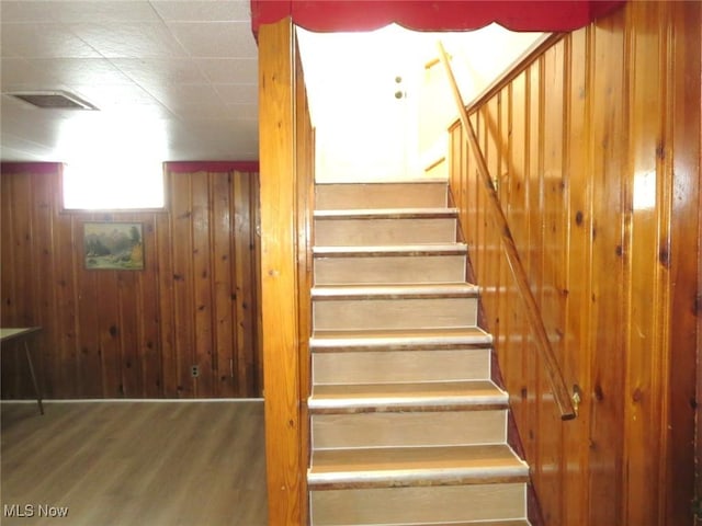 stairway featuring hardwood / wood-style flooring and wood walls