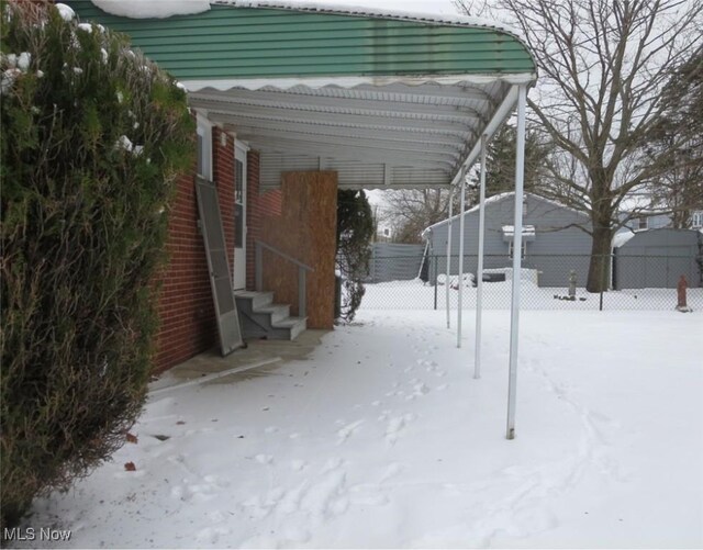 snowy yard featuring a carport