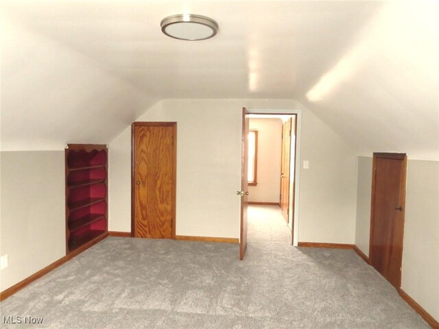 additional living space featuring vaulted ceiling and carpet flooring