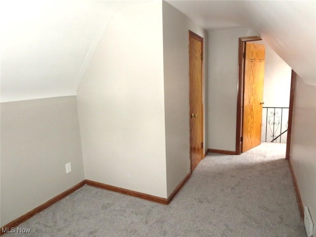 additional living space featuring vaulted ceiling and light carpet