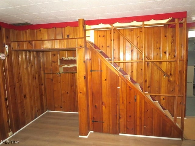 stairway featuring hardwood / wood-style flooring and wood walls