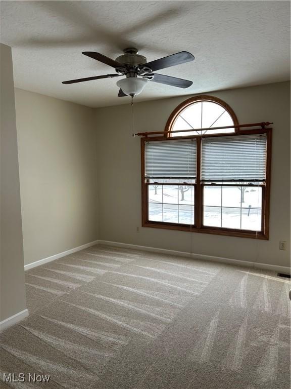 carpeted empty room with ceiling fan and a textured ceiling