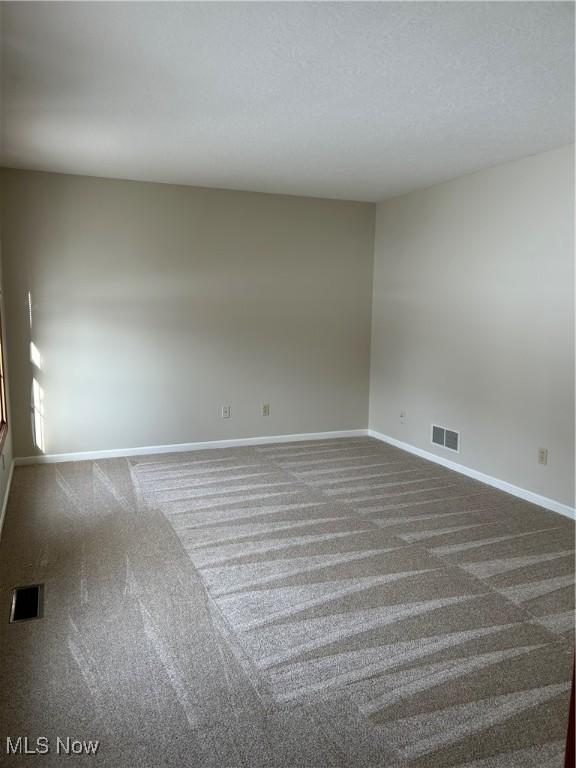 empty room featuring dark colored carpet and a textured ceiling