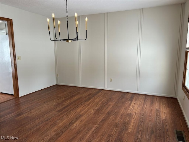 unfurnished dining area featuring dark hardwood / wood-style floors and a notable chandelier