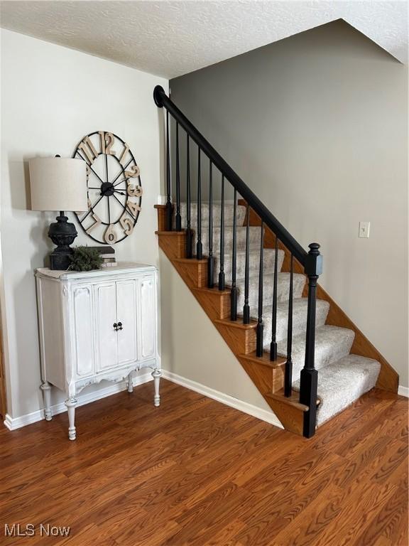 staircase featuring hardwood / wood-style floors and a textured ceiling