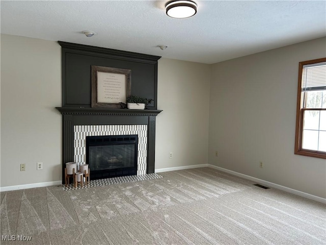 unfurnished living room featuring a tiled fireplace and carpet