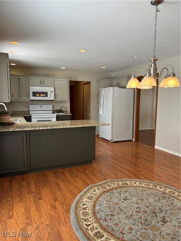 kitchen featuring sink, decorative light fixtures, gray cabinets, white appliances, and light stone countertops