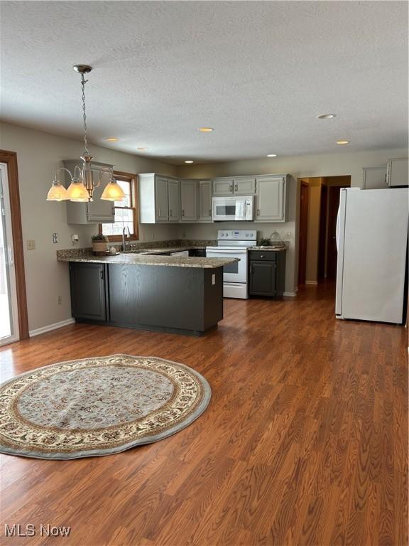 kitchen featuring gray cabinetry, an inviting chandelier, a textured ceiling, hanging light fixtures, and white appliances