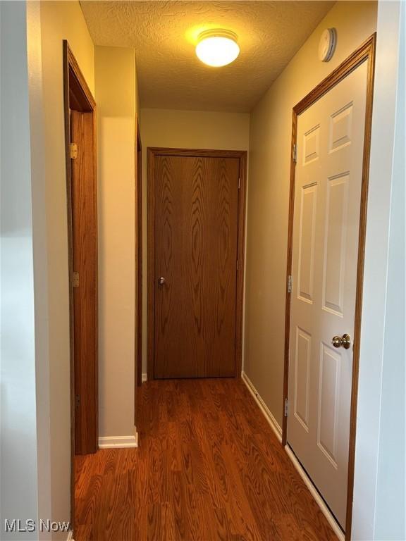 corridor with dark hardwood / wood-style floors and a textured ceiling