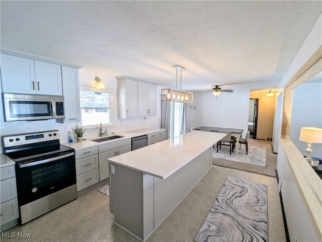 kitchen with sink, a center island, appliances with stainless steel finishes, pendant lighting, and white cabinets