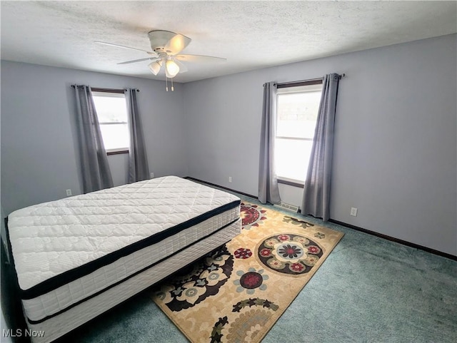 carpeted bedroom with multiple windows, a textured ceiling, and ceiling fan