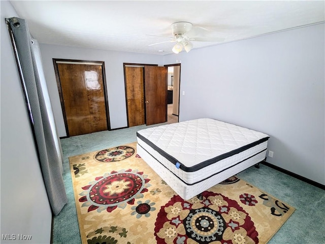 carpeted bedroom featuring multiple closets and ceiling fan