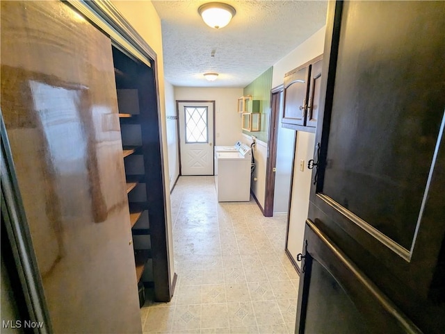 hall featuring independent washer and dryer and a textured ceiling