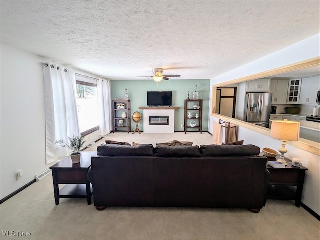 carpeted living room with ceiling fan and a textured ceiling