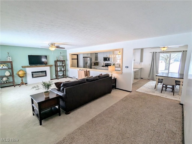 carpeted living room featuring ceiling fan and a textured ceiling