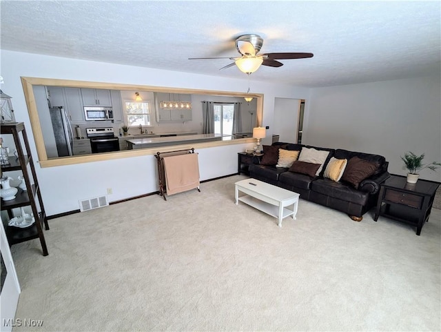 living room with sink, light colored carpet, a textured ceiling, and ceiling fan