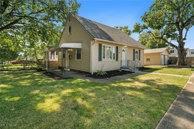 view of front of house featuring an outbuilding, a garage, and a front lawn