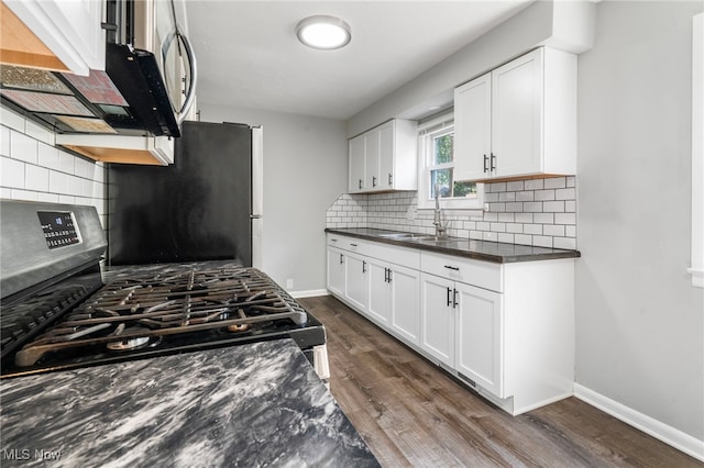 kitchen with dark hardwood / wood-style floors, tasteful backsplash, sink, white cabinets, and stainless steel appliances