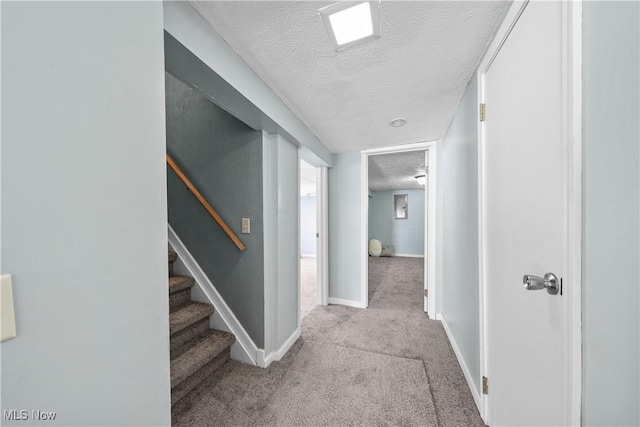 hallway with light carpet and a textured ceiling