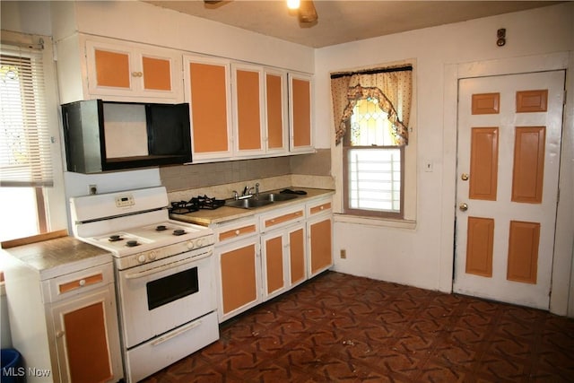 kitchen with sink, ceiling fan, backsplash, white range oven, and white cabinets