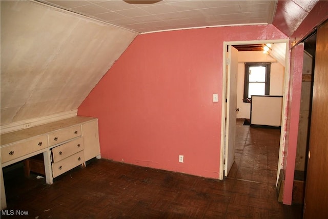 bonus room with dark parquet flooring and vaulted ceiling