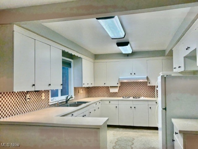 kitchen featuring white cabinetry, white fridge, sink, and kitchen peninsula